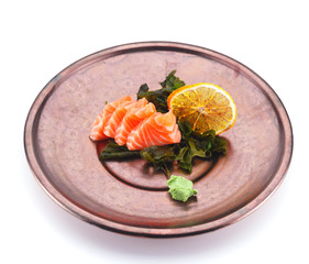 Salmon sashimi with lemon and wasabi on a clay plate isolated on white background