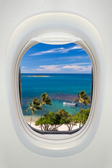 Window of an airplane from inside, view on a tropical beach and sea
