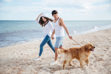 Romantic young couple walking on the sea shore with dog