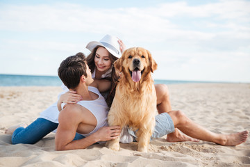 Couple playing with their dog at the seaside