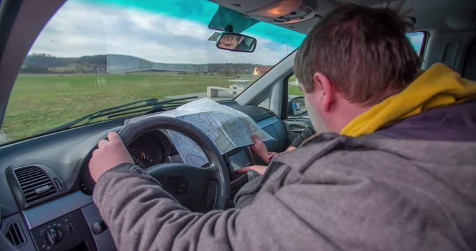 Two men are typing a new address in the garmin. They are about to leave a motorway lay-by and hit the road. Close-up shot.
