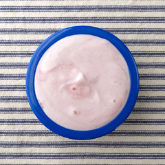 Small bowl of black cherry Greek yogurt top view on a striped tablecloth.