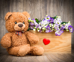 Eustoma flowers in the box and a teddy bear on wooden background