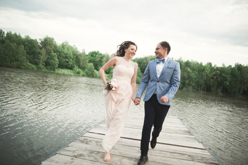 Wedding couple, bride, groom walking and posing on pier