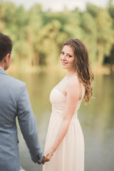 Fototapeta premium Elegant beautiful wedding couple posing near a lake at sunset