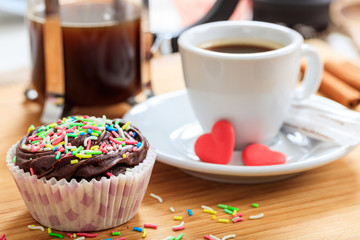 Cup of coffee and a cup cake on a wooden surface