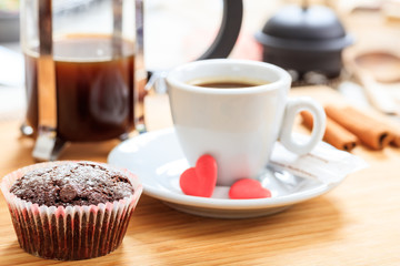 Cup of coffee and a cup cake on a wooden surface