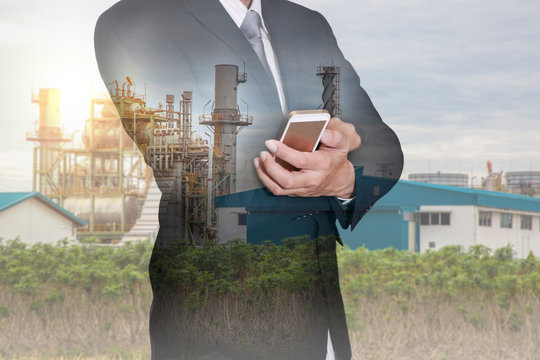 Double Exposure Of Business Man Hand Hold Smart Phone, Mobile And Oil Refinery Industry Plant And Sunset As Energy And Technology Concept.