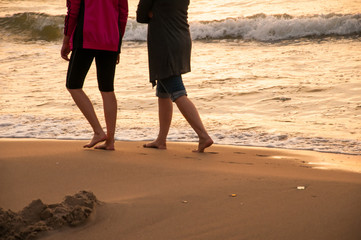 Two girls walking on the beach in sunset time