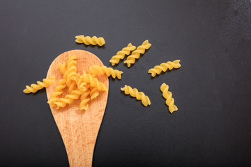 Fusilli pasta in a ladle, black background