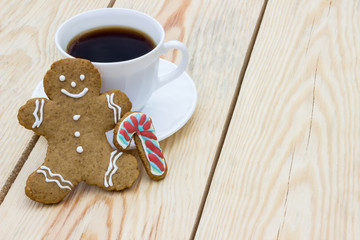 Homemade gingerbread cookie man and cup of coffee on wooden table