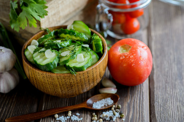 Fresh cucumber salad with fennel and garlic in bowl on wooden board
