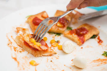 Man's hands picking slices of homemade pizza with a fork; pizza
