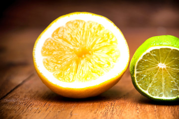 Ripe lemons and limes over black wooden background