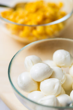 Mozzarella balls in a glass bowl with corn in another glass bowl