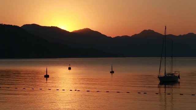 Sailing boat and sunrise behind the mountains in Marmaris, Turunc bay.