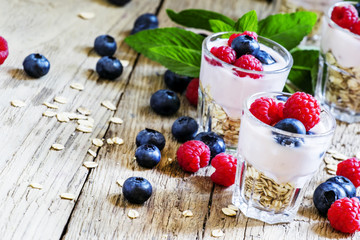 Berry yogurt with muesli, vintage wooden background, selective f