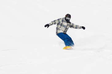 A snowboarder comes down the slope of the mountain