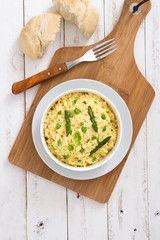 Risotto with asparagus and peas on white wooden table 
