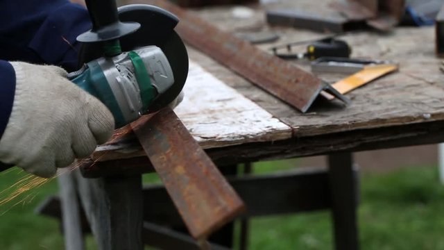 Worker cutting a steel rail with angle grinder

