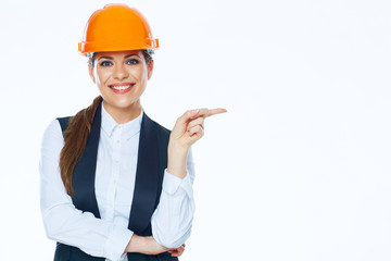 Woman builder in helmet points finger at copy space