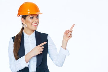 Woman builder in helmet points finger at copy space