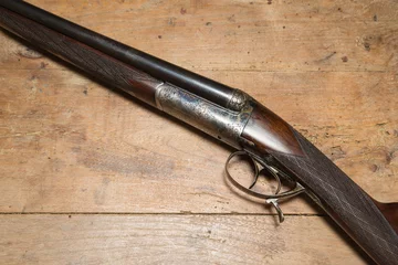 Tuinposter Vintage hunting gun on a wooden background © stsvirkun