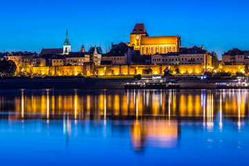 Torun Old Town at night reflected in Vistula river, Poland