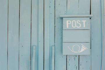 Blue post box on a wooden blue wall 