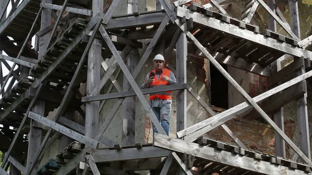 Angry construction worker standing on wooden scaffolding and talking