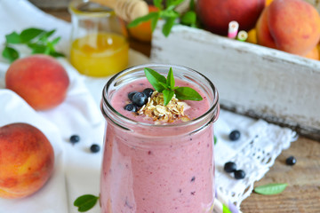 Smoothie of peach, banana and blueberries with oats on a wooden