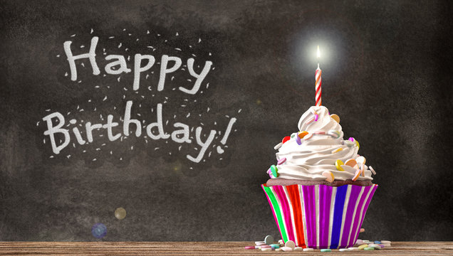 Cupcake à la crème, des bonbons et une bougie sur une table en bois avec Happy Birthday sur le tableau noir. Espace libre  disponible. Rendu 3D
