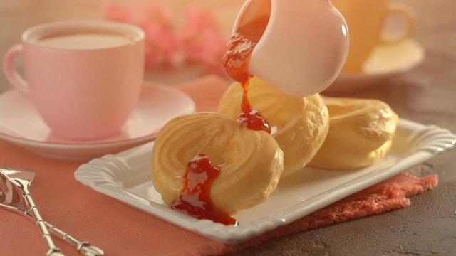 Three fresh ring cakes with jam and cup of trea on the table