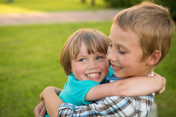 Boy and girl hugging. Green meadow. Funny kids.