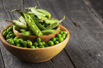 Green peas in wooden bowl on a white background