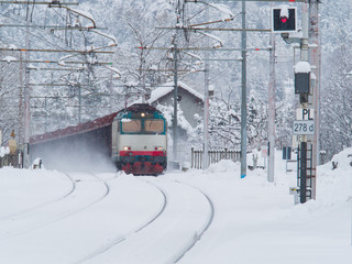 Freight train running on the railway tracks while is snowing