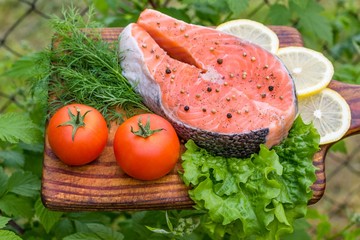 Fresh raw salmon on wooden cutting board. Grass.