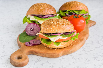 Healthy fast food. Burgers with vegetables and cheese on cutting board.