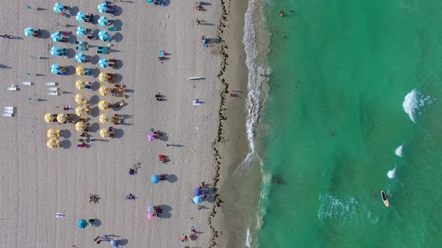 4k AERIAL - Amazing view of a sunny day at the beach - Looking down to umbrellas