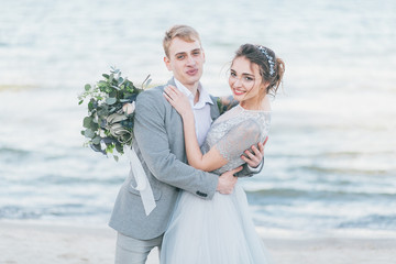 Obraz premium Delighted newly-weds cuddling at the seashore