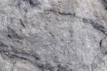 Fototapeta premium Texture raw rough surface of white marble. Background raw white marble stone in its natural form. Semi-precious stone material for making buildings and interior. Industrial raw materials marble.
