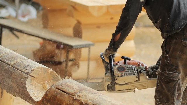 Man cuts off beam chainsaw for future home. Construction works with a wooden structure. Close up