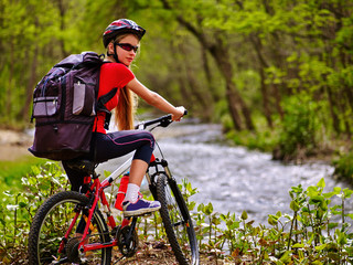 Obraz premium Bicycle girl. Girl with big rucksack rides bicycle. Girl cycling fording throught water . Cycling trip is good for health. Cyclist turned back.