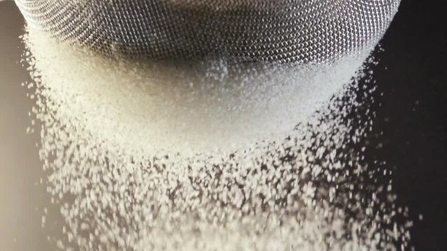 Flour falling through a metal sieve