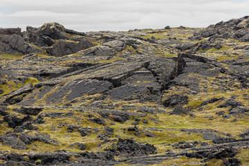 Icelandic landscape of volcanic ground and green moss and volcano's waterfalls and mountains
