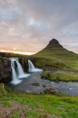 Fototapeta premium Amazing top of Kirkjufellsfoss waterfall with Kirkjufell mountain in the background on the north coast of Iceland's Snaefellsnes peninsula taken white a long shutter speed. 