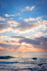 Naklejka na ściany i meble Beautiful sunrise over the sea. Sun beams break through the clouds.