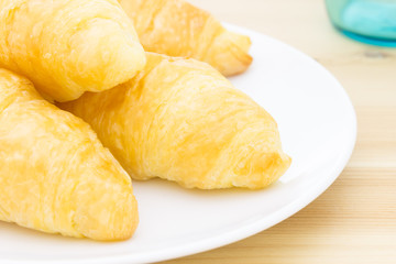 Croissant or Bread on White Dish on Wood Table and Glass