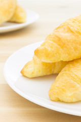 Croissant or Bread on White Dish on Wood Table Portrait View