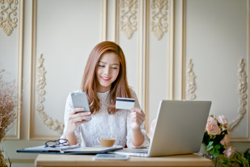 Happy woman shopping online, holding credit card.